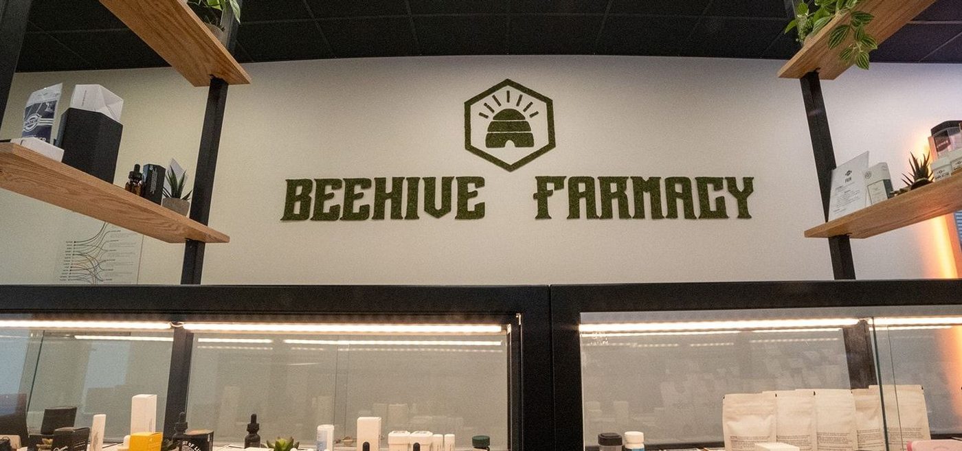 Beehive Farmacy logo on wall above display cases of cannabis products
